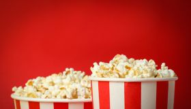 Paper cups with popcorn on red background