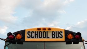 Front top view of a yellow school bus on a sky with clouds